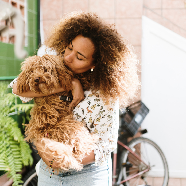 Woman holding and kissing her spoodle. Pet cremation services.
